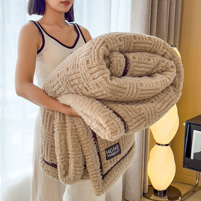 Person holding a beige textured blanket with 'HOME' label in a room setting.