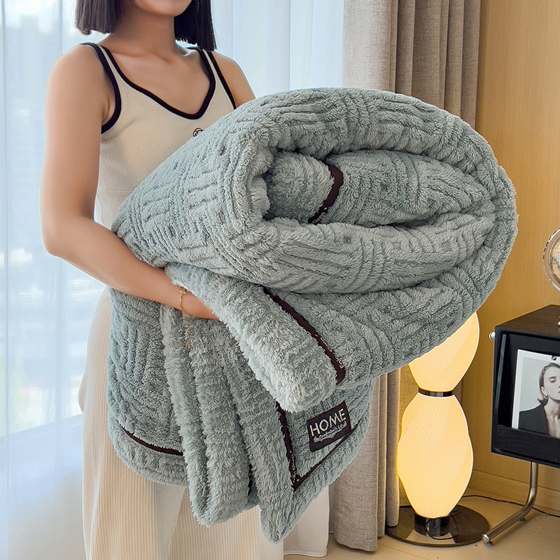 Person holding a textured gray blanket with 'HOME' branding in a room setting.