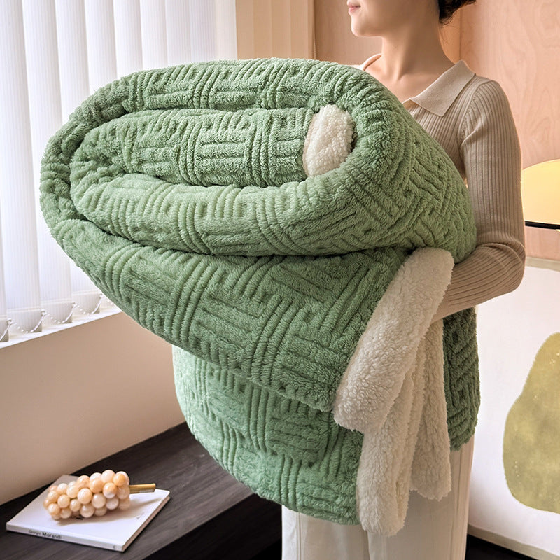 Person holding a green textured blanket indoors