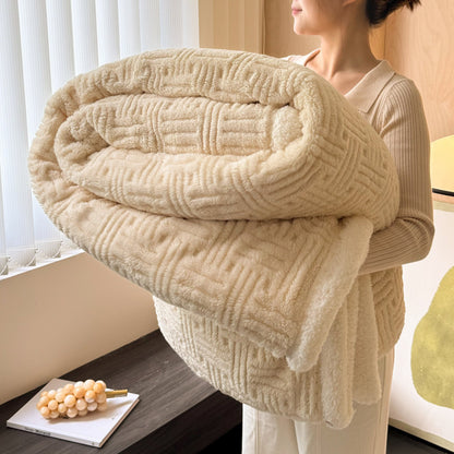 Person holding a large beige textured blanket in a room with a window and decorative items.
