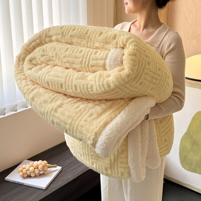 Person holding a large folded yellow blanket in a room with a window and decorative items.