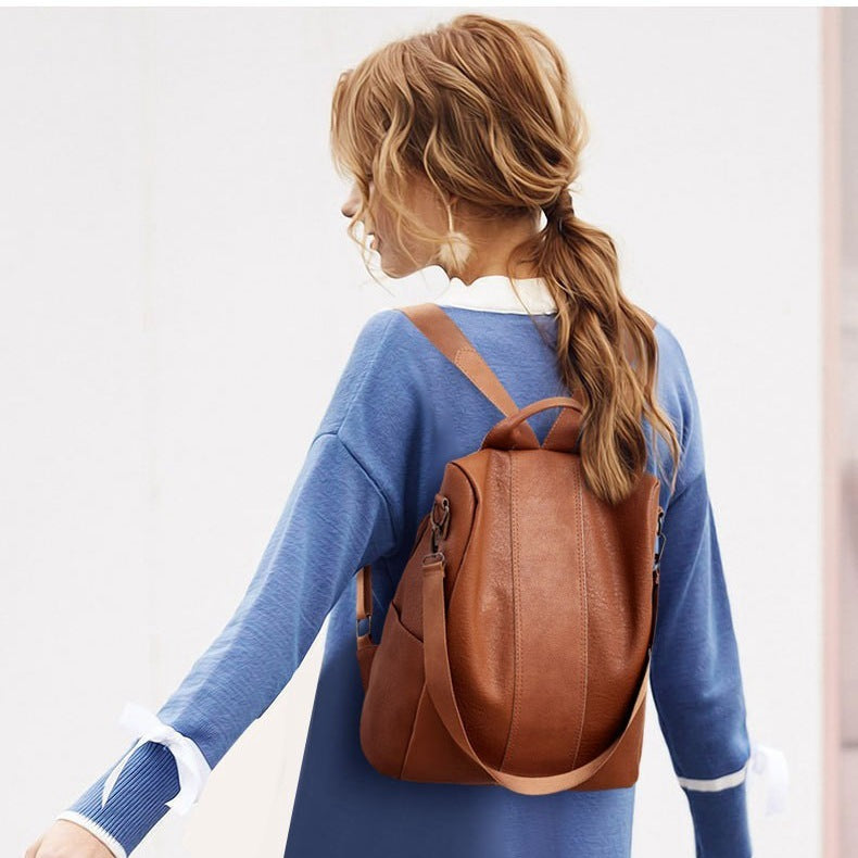 Person wearing a brown leather backpack with a plain background