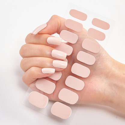 Hand holding a set of light pink nail extensions on a white background