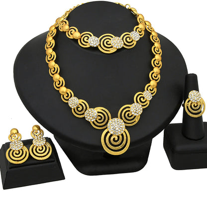 Gold necklace with circular design and matching earrings on a black stand.