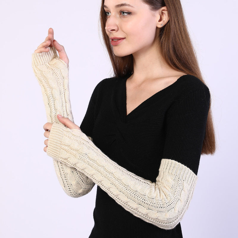 Woman wearing a black sweater with cream-colored arm warmers on a white background
