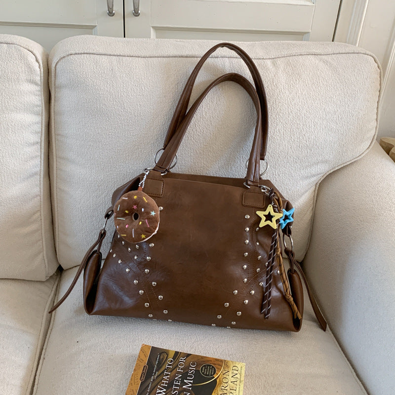 Brown handbag with decorative elements on a beige couch