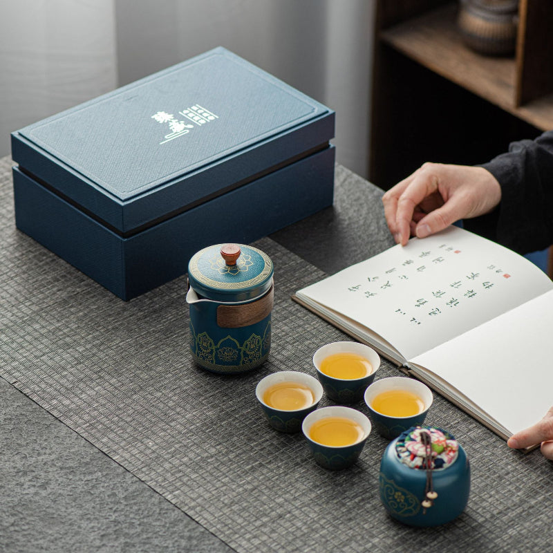 Tea set with cups and a teapot on a table next to an open book.