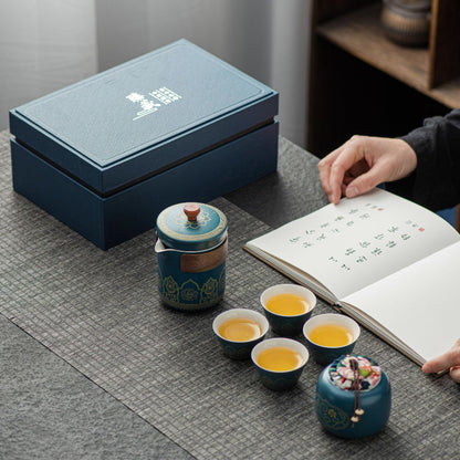 Tea set with cups and a teapot on a table next to an open book.