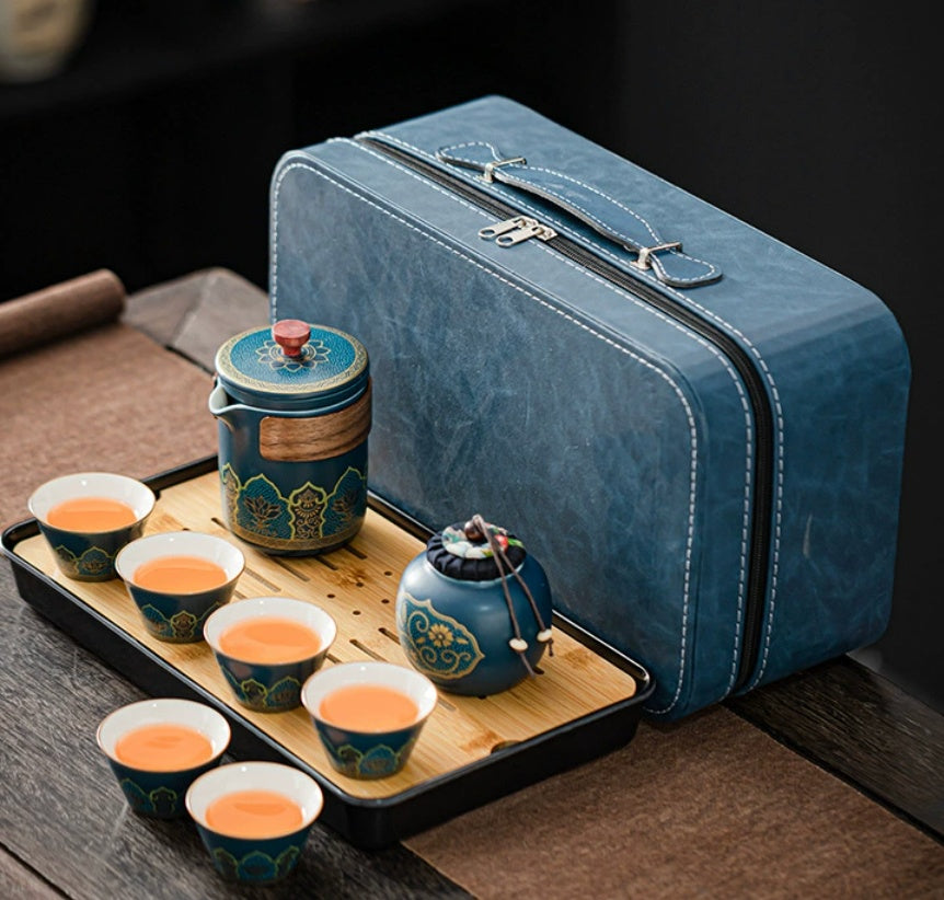 Blue travel tea set with teapot, cups, and tray on a wooden surface.