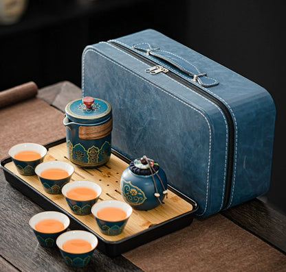 Blue travel tea set with teapot, cups, and tray on a wooden surface.