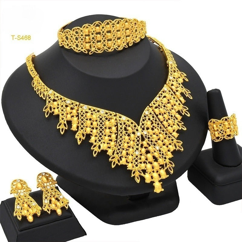 Gold jewelry set including necklace, earrings, bracelet, and ring on a black stand.