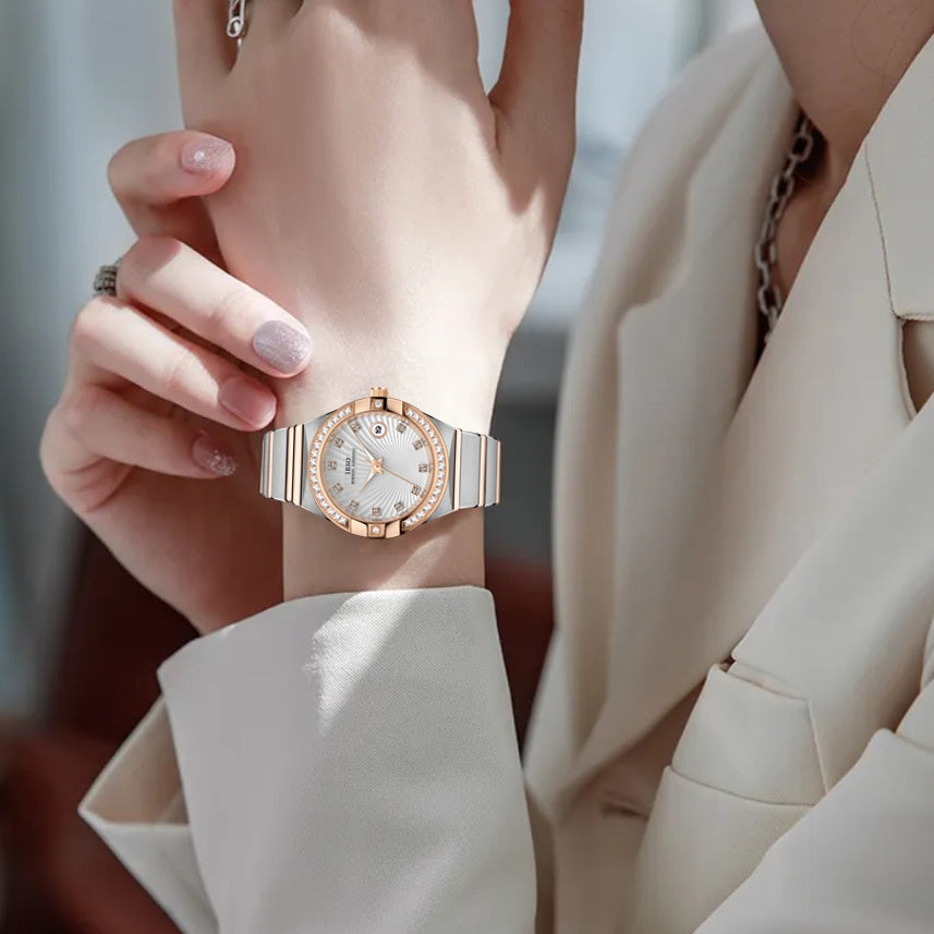 Close-up of a hand wearing a rose gold watch with a white face.