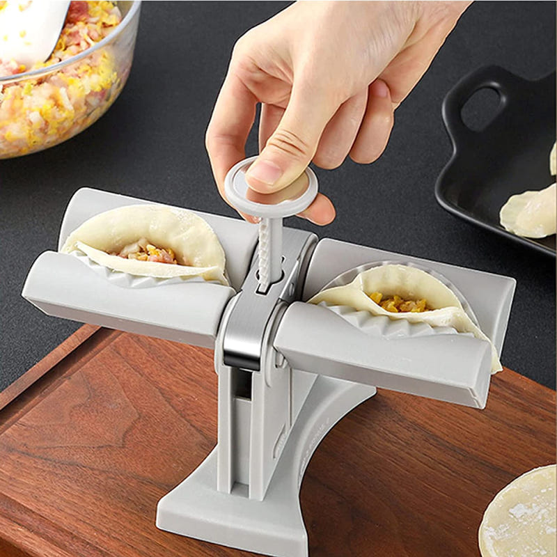 White dumpling maker press with handle, shaping filled dough in a tray