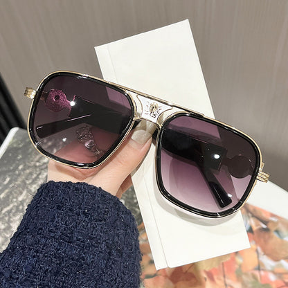 Sunglasses with gradient purple lenses held by a hand against a blurred background