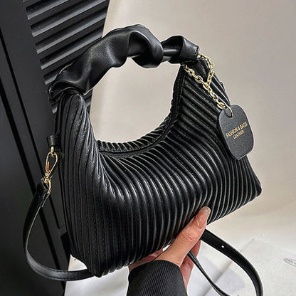 Black ribbed handbag held by a hand with a blurred background