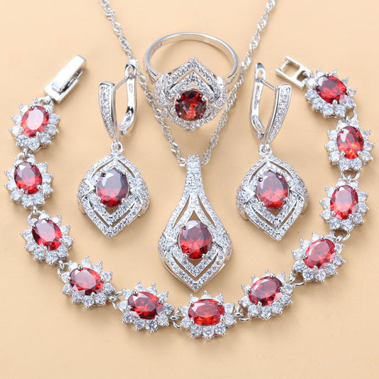Jewelry set with red gemstones and silver accents on a beige background
