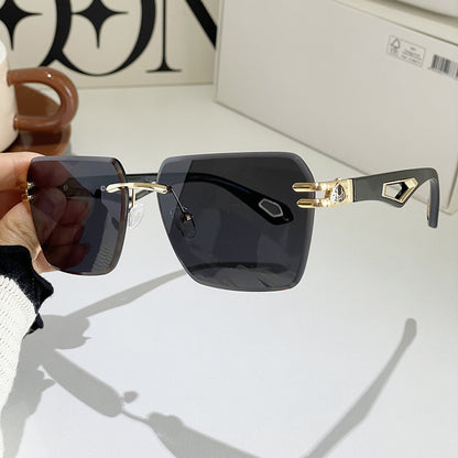 Sunglasses with gold accents held by a hand on a light background