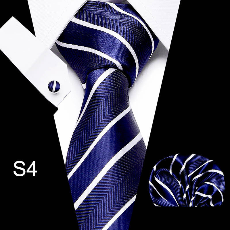 Navy blue tie with white stripes, cufflink, and pocket square on a black and white background.