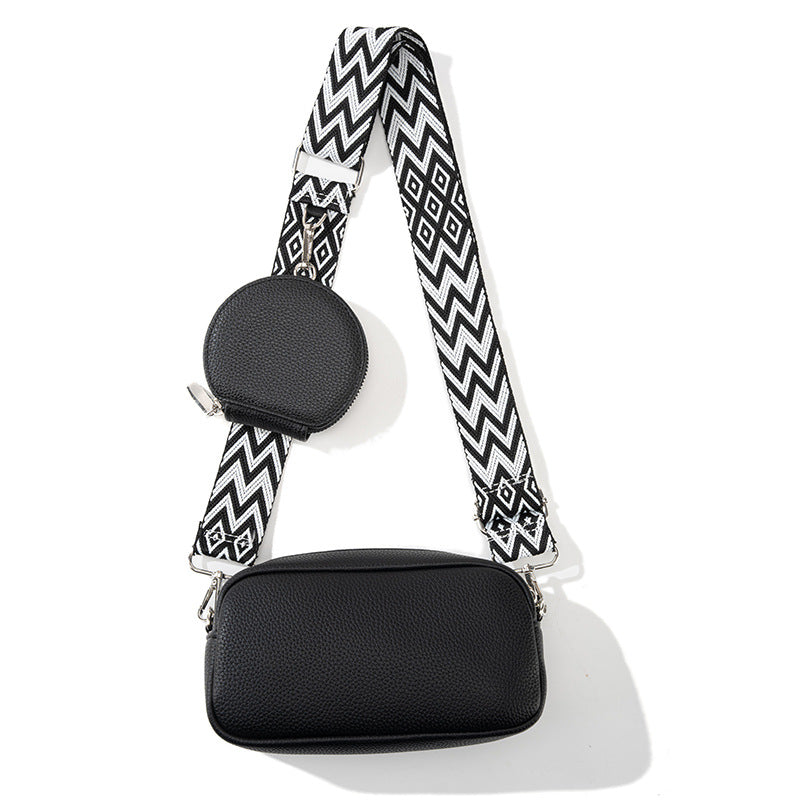 Black handbag with a black and white zigzag strap on a white background