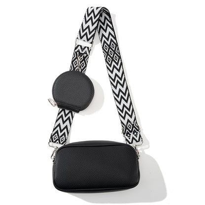 Black handbag with a black and white zigzag strap on a white background