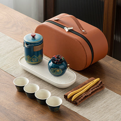 Tea set with ceramic teapot, cups, and a carrying case on a wooden table.