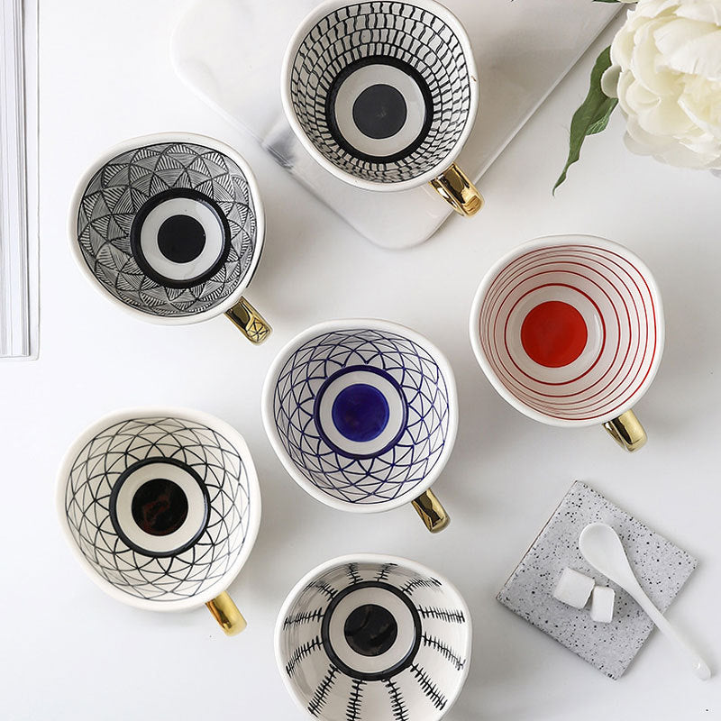 Set of decorative mugs with geometric patterns on a white surface.