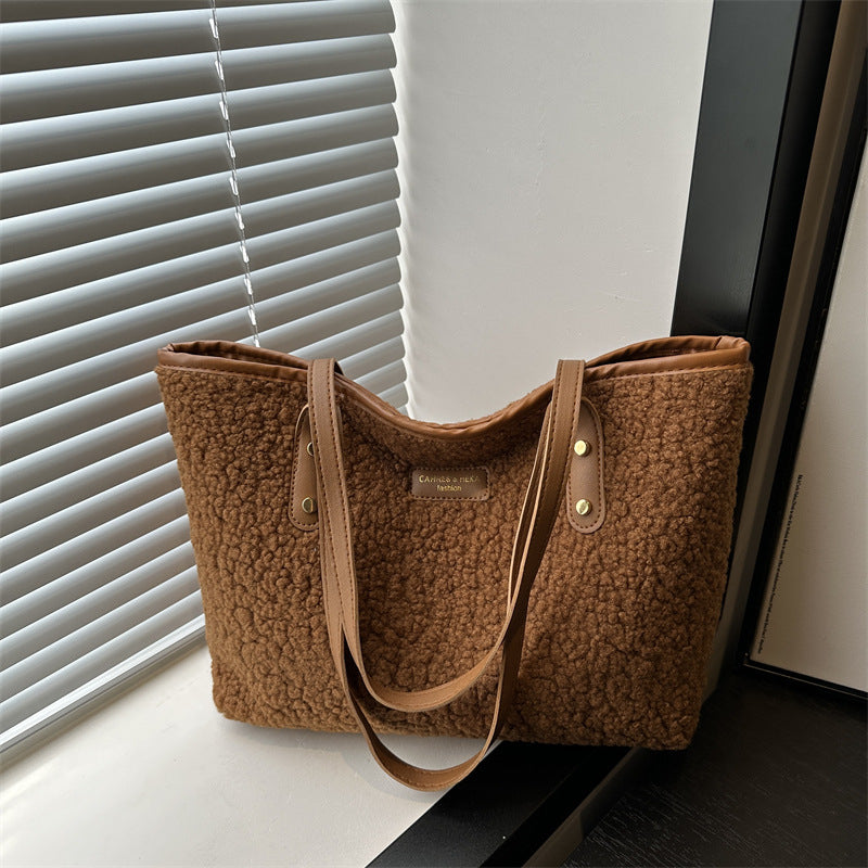 Tan-brown furry tote shoulder bag with dual handles and front logo patch
