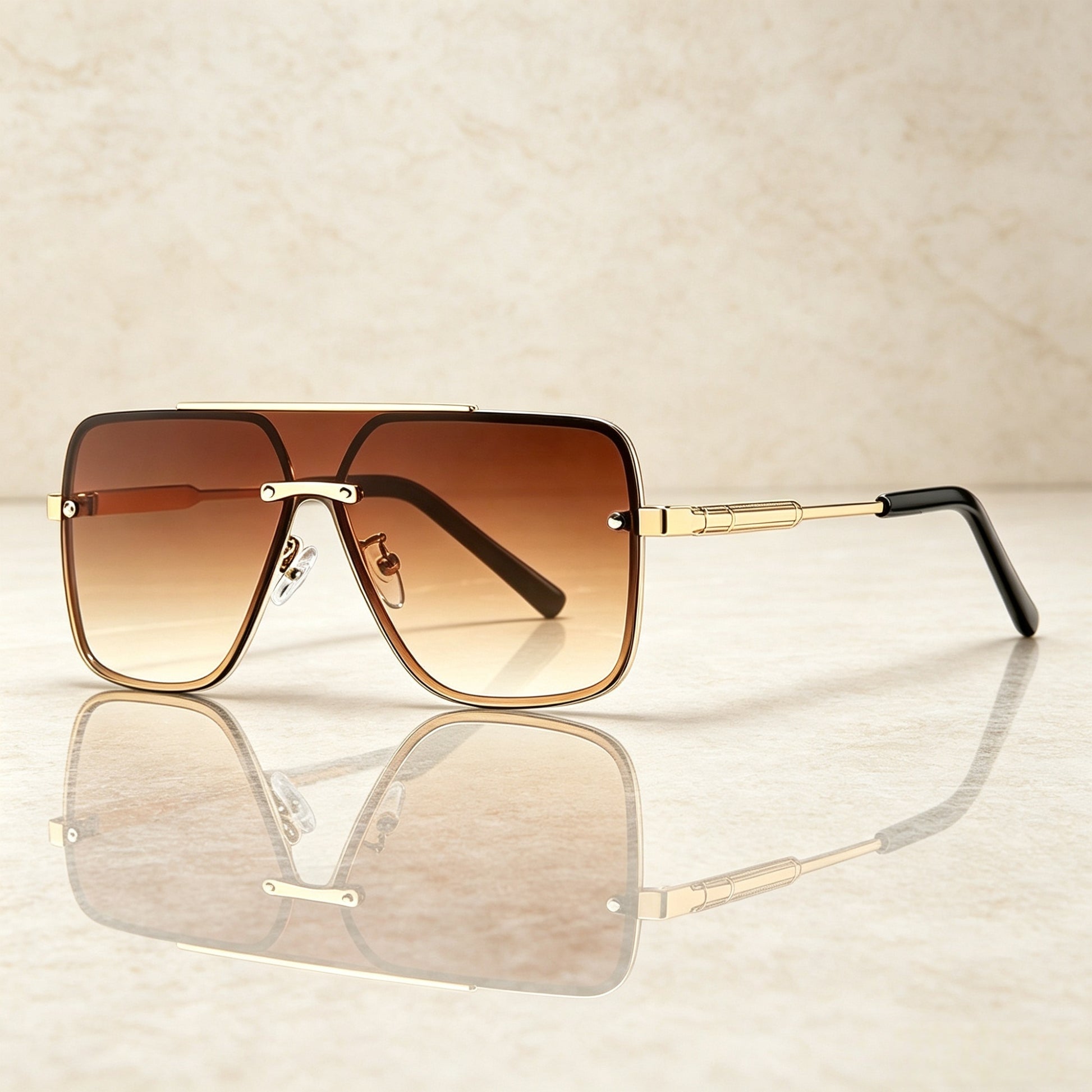 Sunglasses with gold frame and brown gradient lenses on a reflective surface.