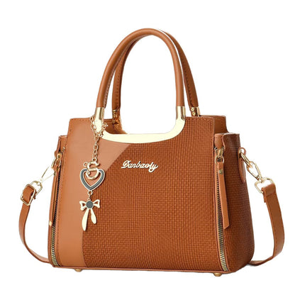 Cognac brown small square crossbody bag with top handles and gold zipper, heart and bow charm