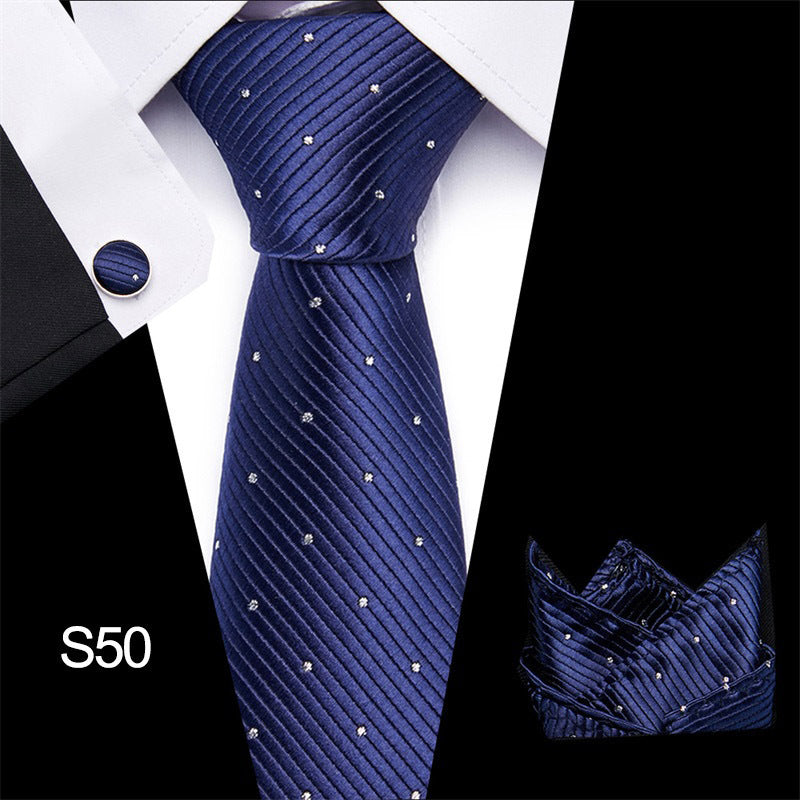 Navy blue tie with subtle pattern, matching pocket square, and cufflinks on a white shirt.