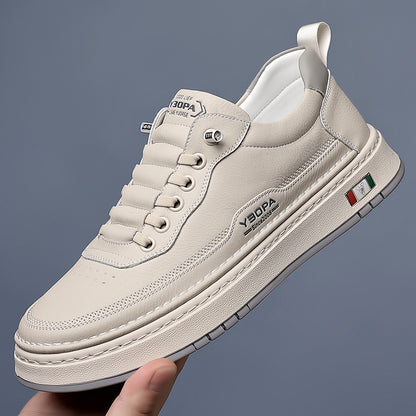 Beige sneaker with brand logo held by a hand against a gray background
