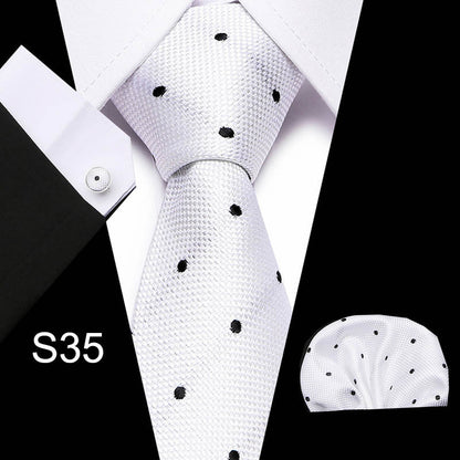 White tie with black polka dots and matching pocket square on a black and white background