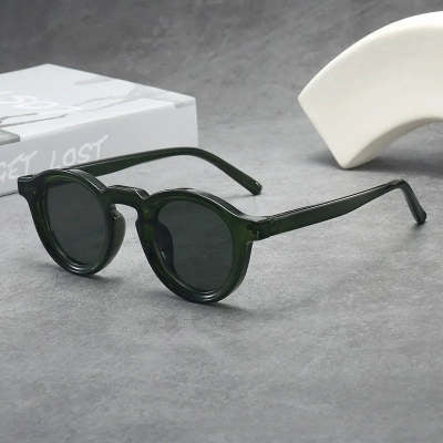 Green sunglasses on a gray surface with a white box in the background