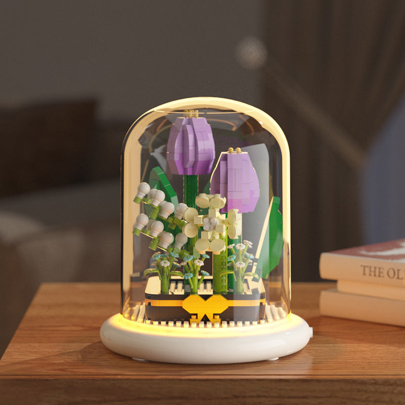Decorative lamp with floral design inside a glass dome on a wooden surface.