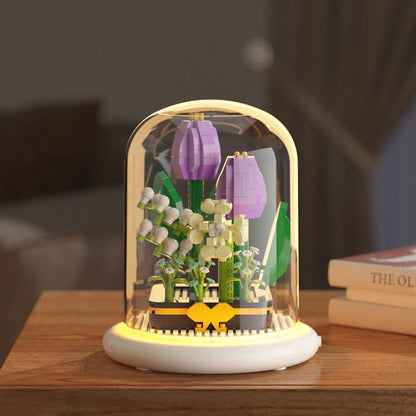Decorative lamp with floral design inside a glass dome on a wooden surface.