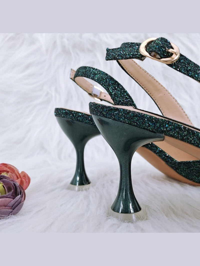 Green glitter high-heeled shoes on a white background with flowers.