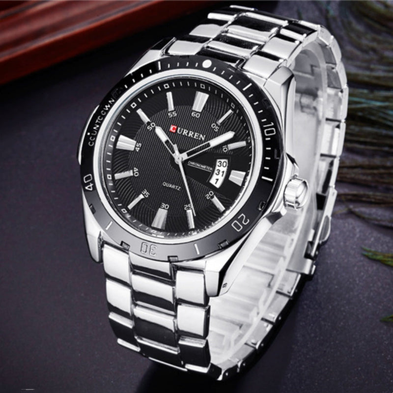 Silver wristwatch with black dial on a dark surface