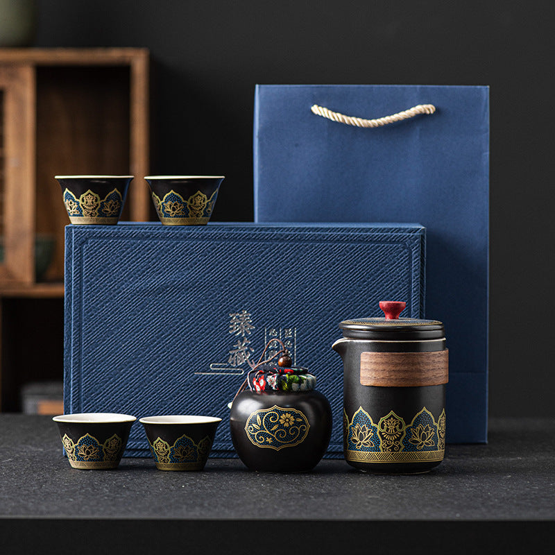 Tea set with decorative elements on a dark surface, featuring a blue gift box.