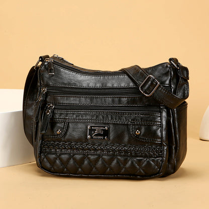 Black leather handbag with braided detail on a beige background