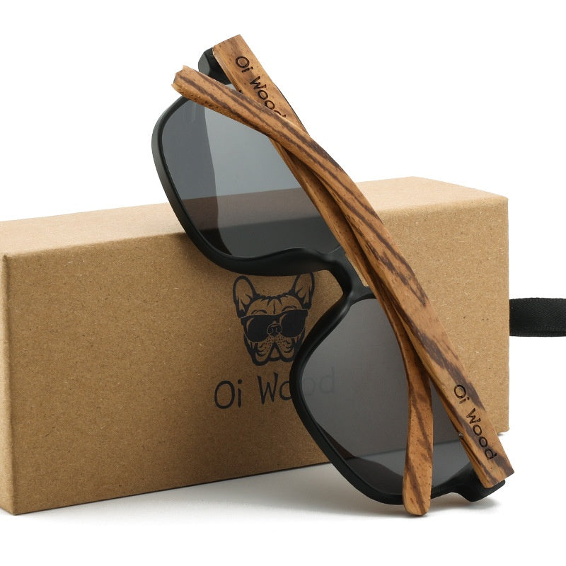 Wooden-framed sunglasses with black lenses on a branded box