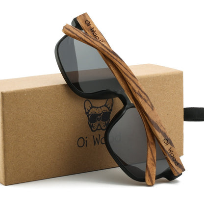Wooden-framed sunglasses with black lenses on a branded box