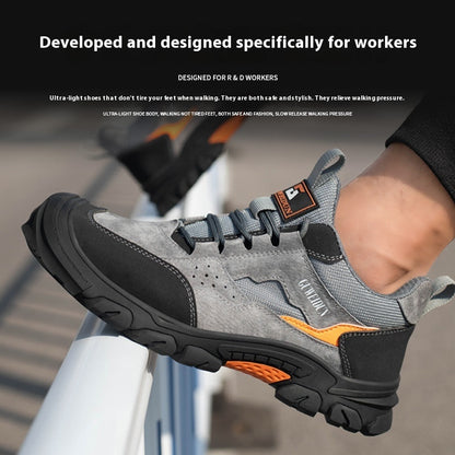 Gray and black work shoe with orange accents, worn by a person, on a blurred background.