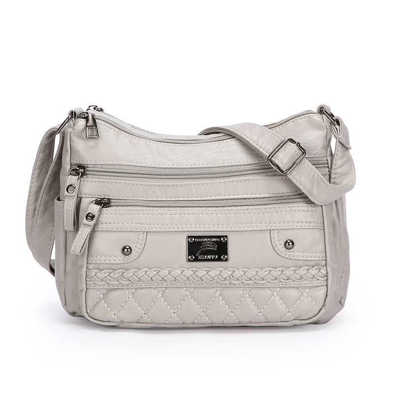 Gray quilted handbag with multiple zippers on a white background