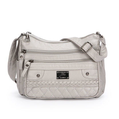 Gray quilted handbag with multiple zippers on a white background