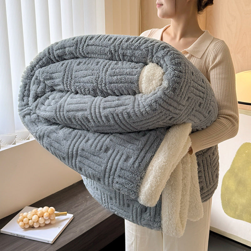 Person holding a large gray textured blanket indoors.