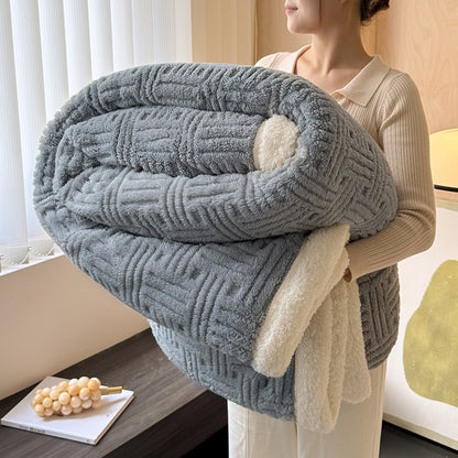 Person holding a large gray textured blanket indoors.
