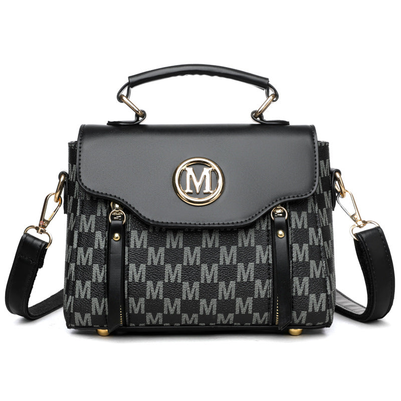 Black handbag with gold accents and a patterned strap on a white background
