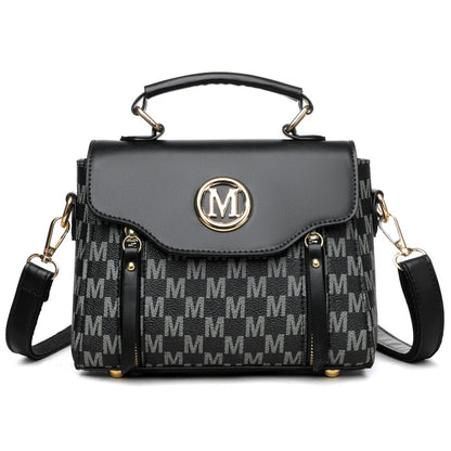 Black handbag with gold accents and a patterned strap on a white background