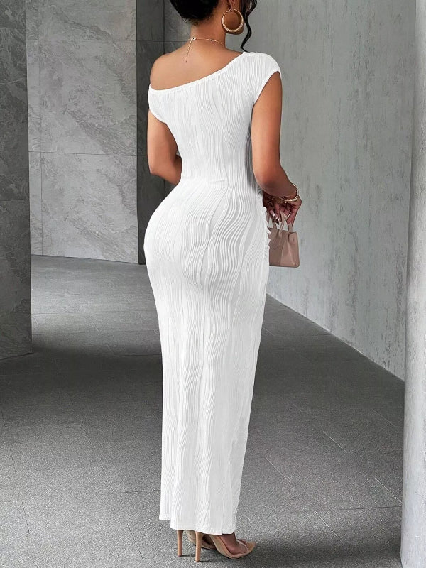 Woman wearing a white one-shoulder dress in a gray room.