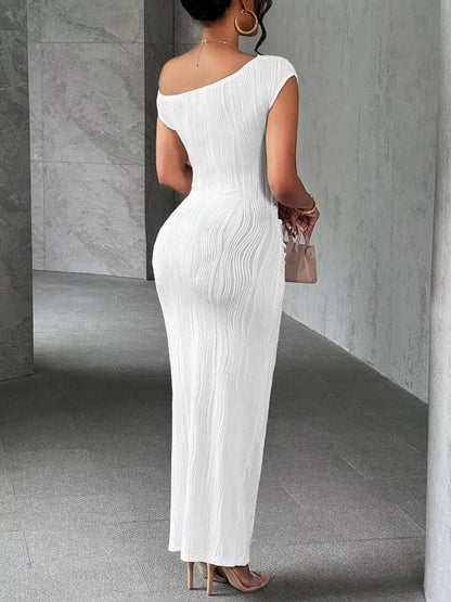 Woman wearing a white one-shoulder dress in a gray room.